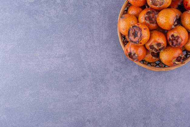 Free photo medlars isolated in a wooden platter on the ground