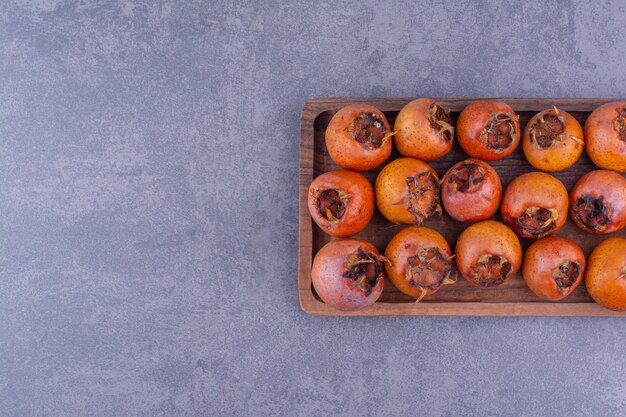 Medlars isolated in a wooden platter on the ground