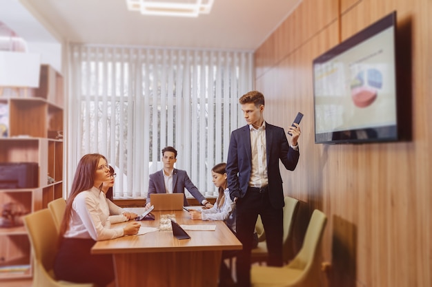 Foto gratuita incontro degli impiegati al tavolo, guardando la presentazione con gli schemi in tv