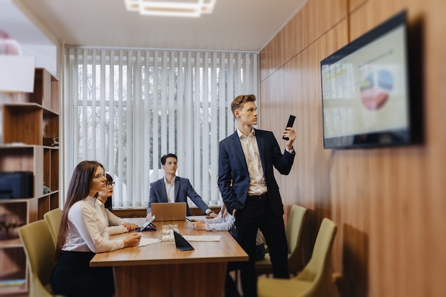 Incontro degli impiegati al tavolo, guardando la presentazione con gli schemi in tv