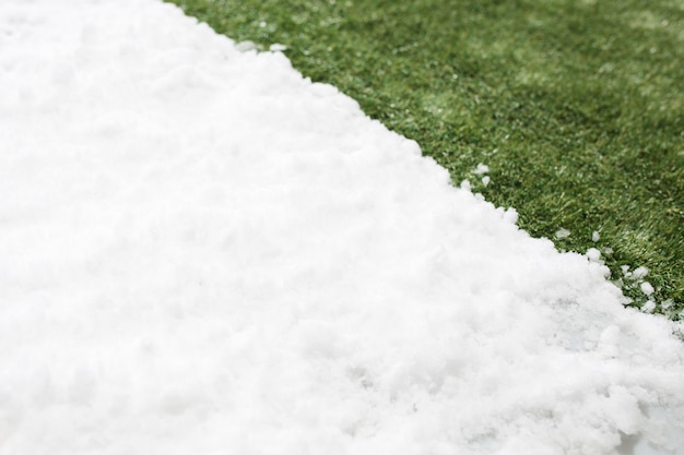 Free photo meeting white snow and green grass close up. between winter and spring concept background.