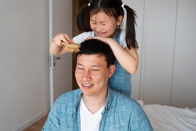 Meidum shot kid brushing father's hair
