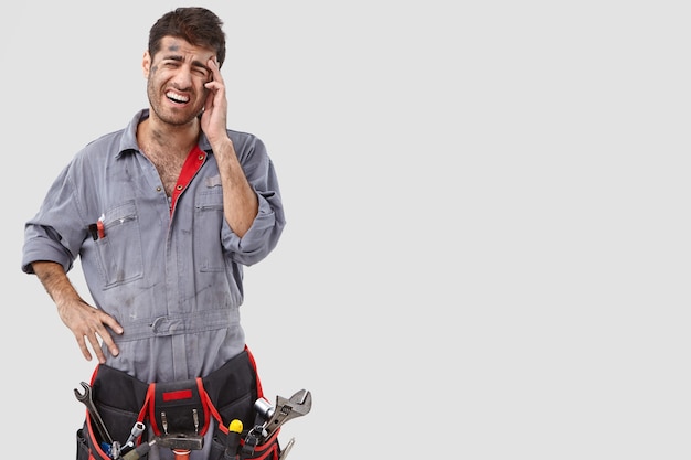 Free photo melancholic handyman posing against the white wall