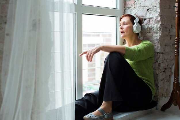 Melancholic senior woman listening music