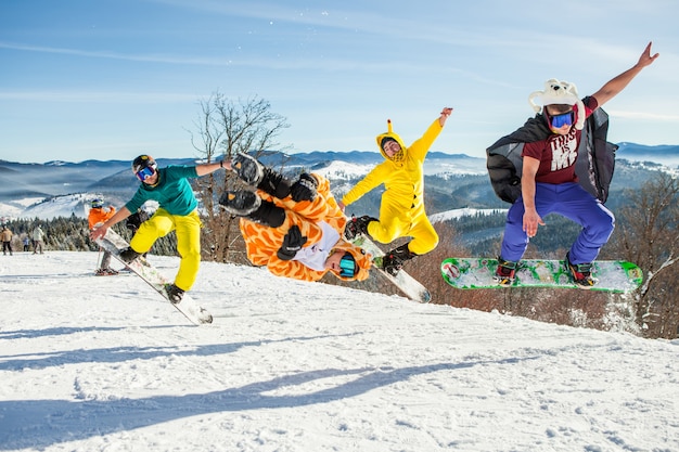 山を背景に彼のスノーボードでジャンプする男性ボーダー