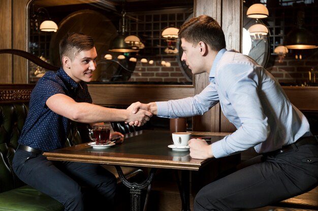 Men in cafe shaking hands