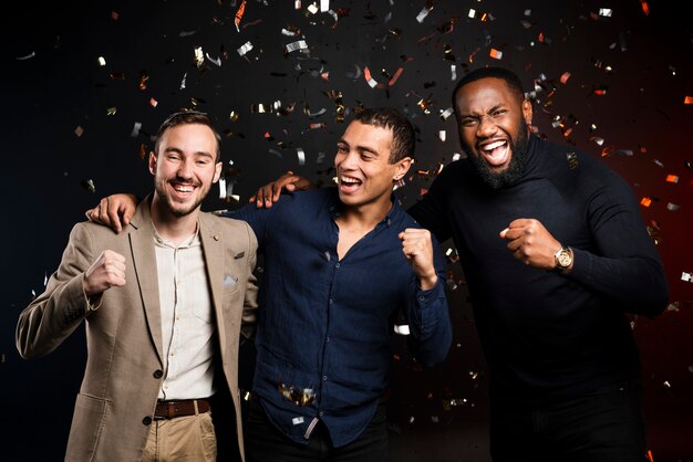 Men cheering surrounded by confetti at party