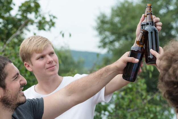 Men clinking bottles in countryside