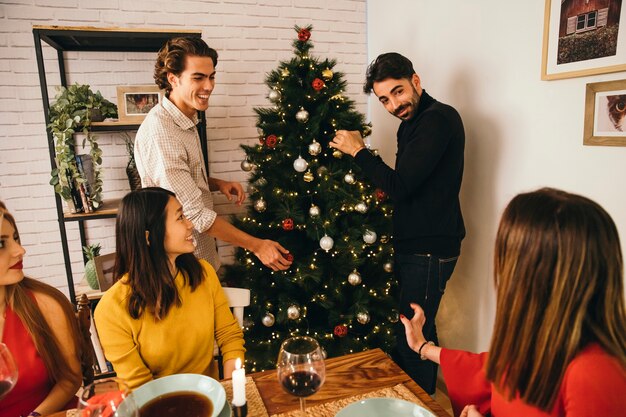 Men decorating tree at christmas dinner