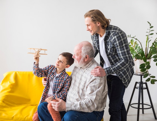 Free photo men of different generations looking at toy plane