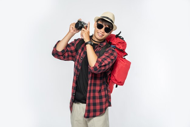 Men dressed to travel, wearing glasses and hats Carrying a bag and carrying a camera