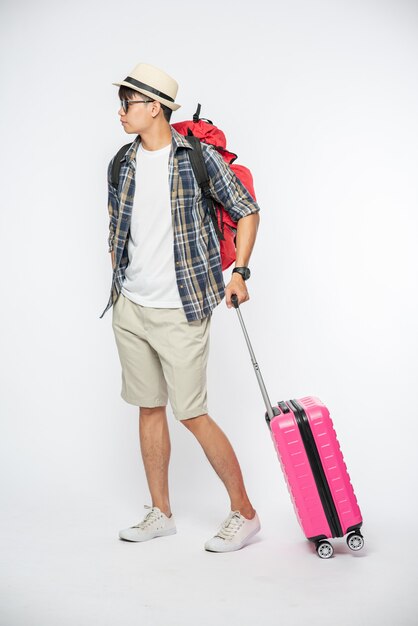 Men dressed to travel, wearing glasses and hats, carrying bags and luggage