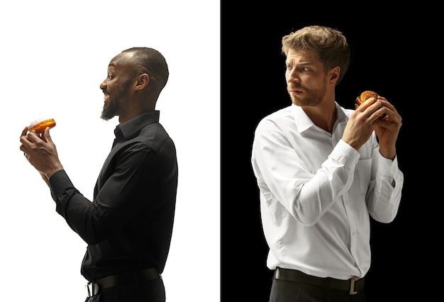 Мужчины едят гамбургер и пончик на черно-белом пространстве