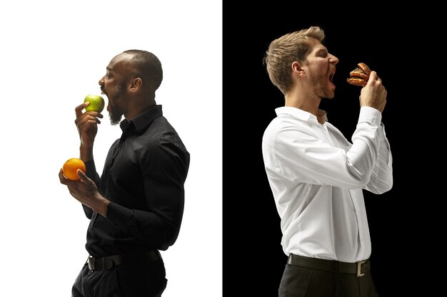 Men eating a hamburger and fresh fruits on a black and white space