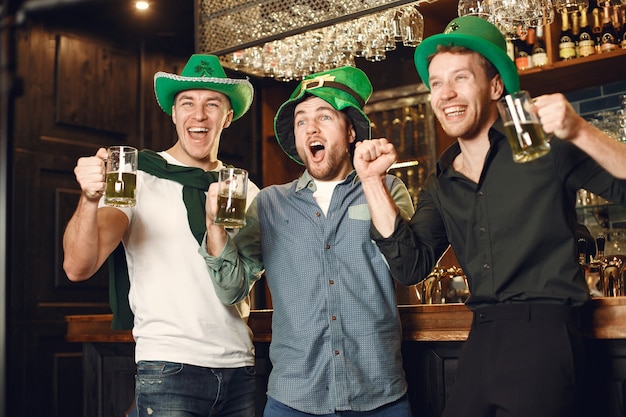 Мужчины в зеленых шляпах. Друзья отмечают День Святого Патрика. Праздник в пабе.