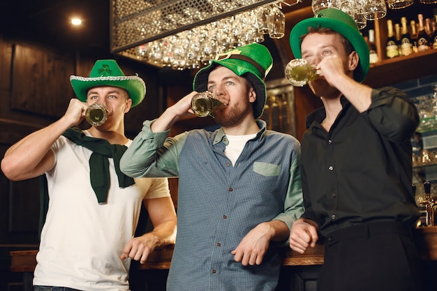 Men in green hats. Friends celebrate St. Patrick's Day. Celebration in a pub.