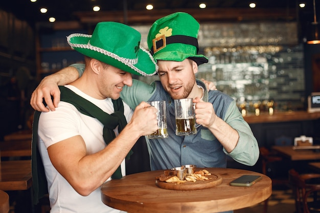 Men in green hats. Friends celebrate St. Patrick's Day. Celebration in a pub.