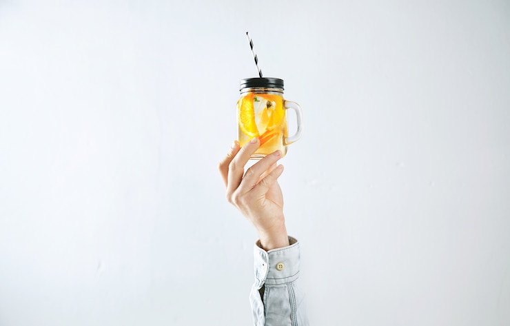 Free Photo men hand presents homemade cold lemonade from oranges, sparkling water and ice cubes isolated on white.
