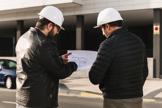 Free photo men in helmets looking at plans