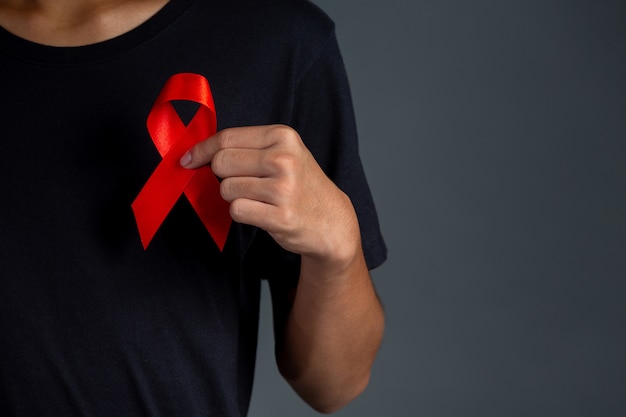 赤いリボンを保持している男性。概念的な認識。 HIV。世界エイズデーと世界性的健康デー。