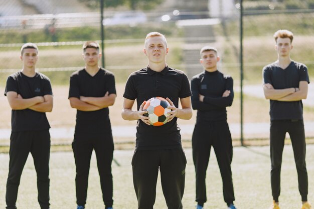 男性は公園でソーサーをします。ミニサッカーのトーナメント。黒のスポーツスーツを着た男。