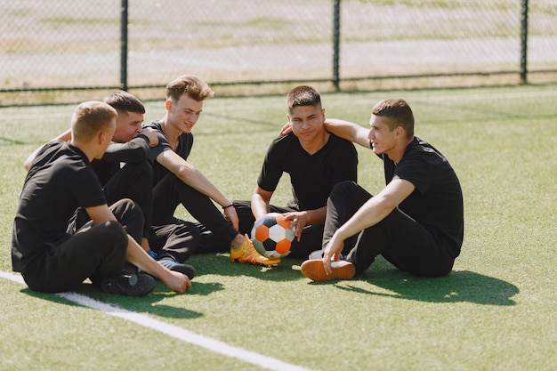 Free photo men play socer at the park. tournament on mini-footbal. guy in a black sportsuits.