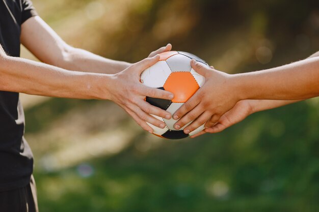 Men play socer at the park. Tournament on mini-footbal. Guy in a black sportsuits.