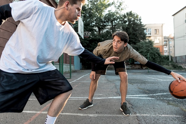 Foto gratuita uomini che giocano a basket sul campo urbano