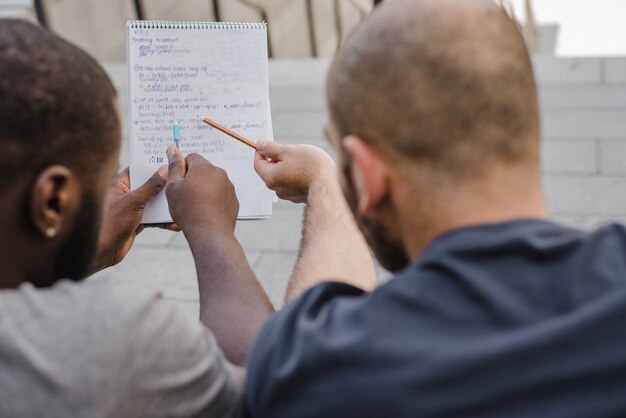 Men pointing at notebook outside