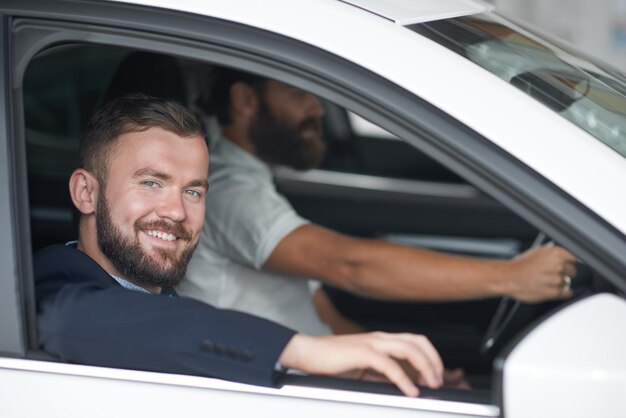Men posing in car cabin in car dealership