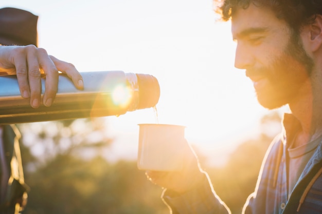 Men pouring drink in nature