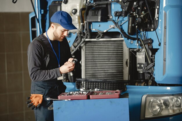 Men repair a truck. Man teaches repair a car. Two men in uniform