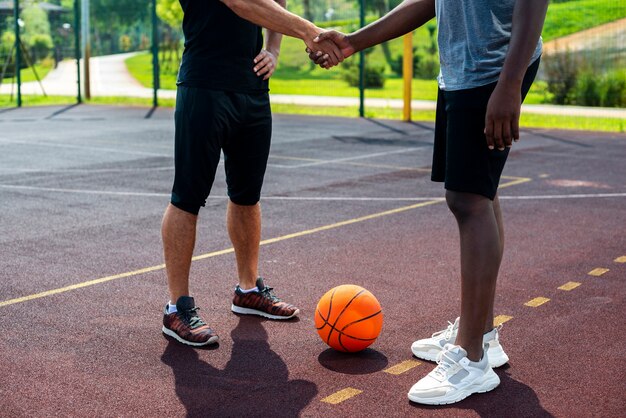 Мужчины пожимают друг другу руки на баскетбольной площадке