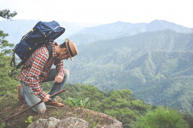 男性は座って、熱帯林の山々をバックパックで眺めます。冒険、旅行、登山。