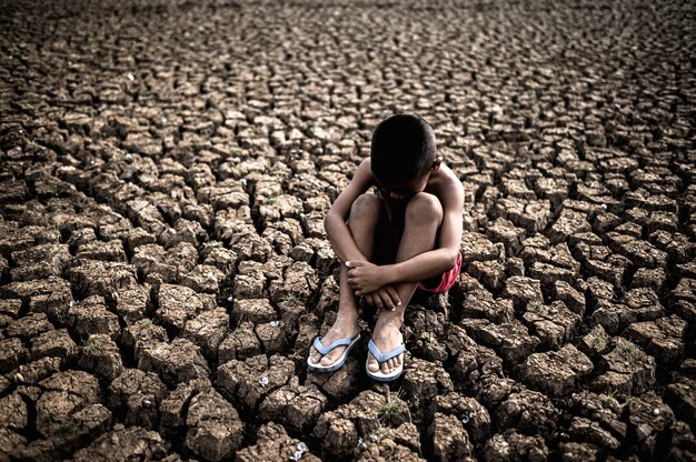 Men sitting hugging their knees, bent, bent on the dry soil, global warming