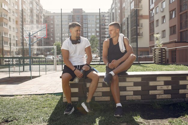 Men in sports clothes have a rest after training in a park