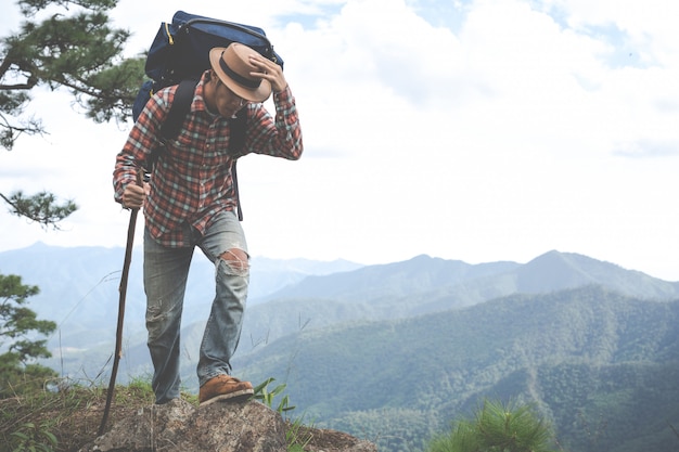 男性は、森のバックパックで熱帯林の山を見るために立ちます。冒険、旅行、登山。