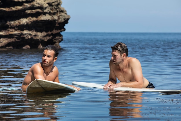 Free photo men surfing together in the ocean