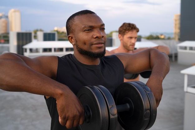 Men training together outdoors with weights