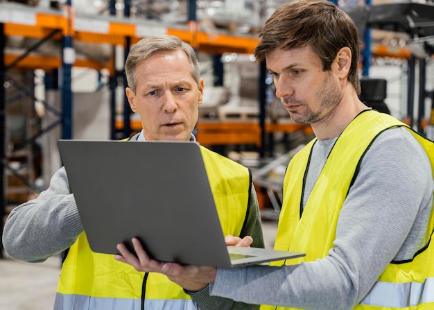 Foto gratuita uomini in magazzino che lavorano al computer portatile