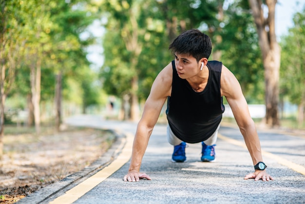 Men wear black shirts with muscles push up on the street.