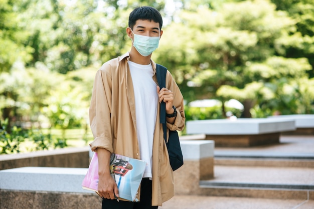 Men wear masks, carry books, and carry a backpack on the stairs.