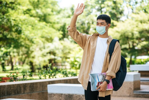 남자들은 마스크를 쓰고 책을 들고 계단에 배낭을 가지고 다닙니다.