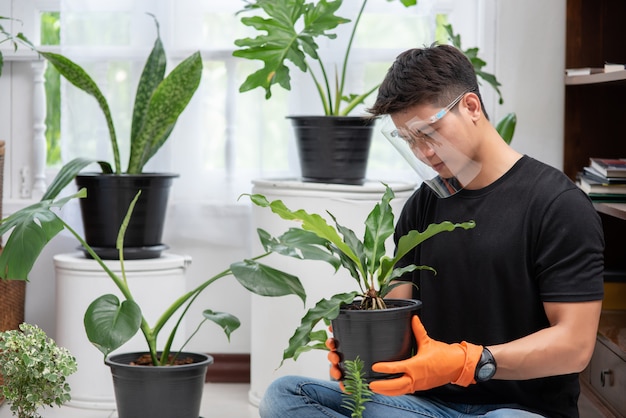 Men wearing orange gloves and planting trees indoors.