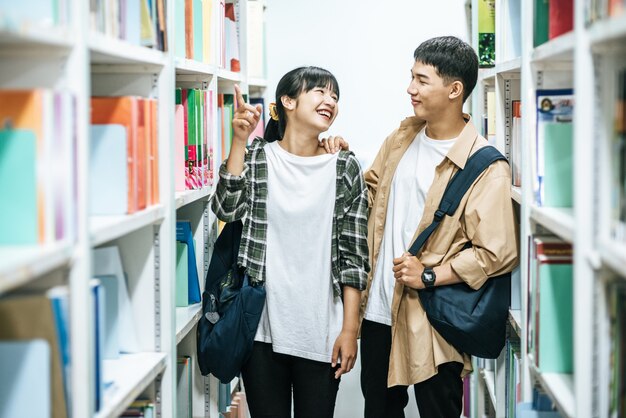 Men and women carrying a backpack and searching for books in the library.