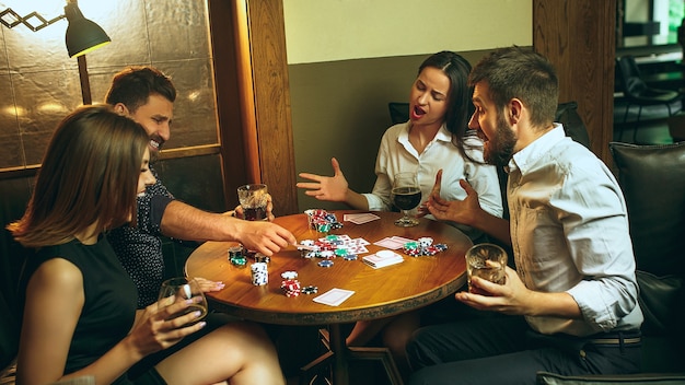 Free photo men and women playing card game. poker, evening entertainment and excitement concept