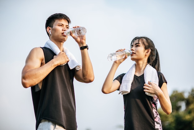 男性と女性は運動後に水を飲むために立っています。