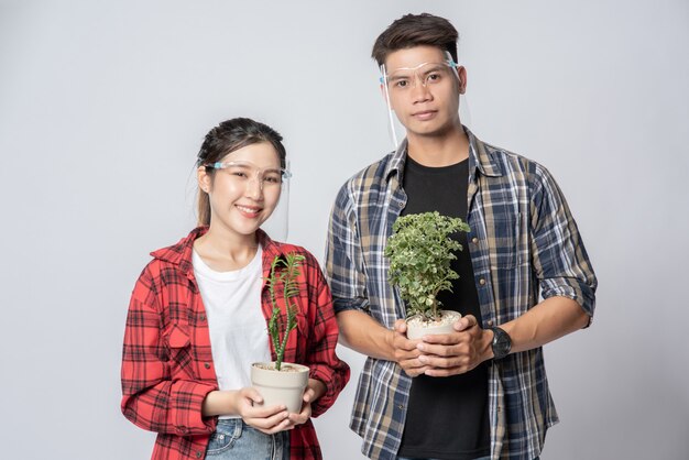 Men and women standing and holding plant pots in the house