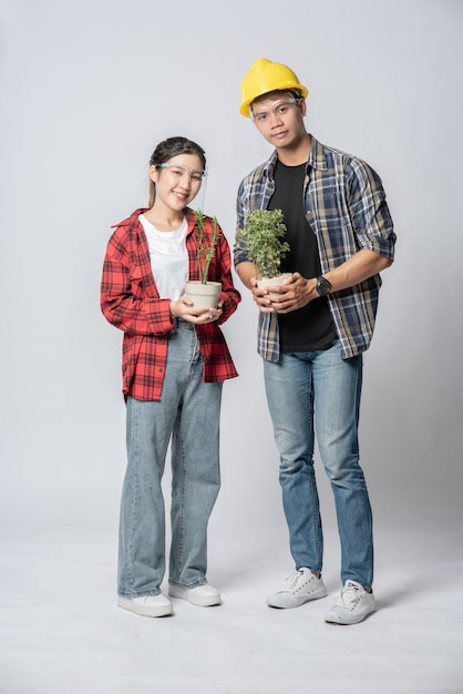 Men and women standing and holding plant pots in the house