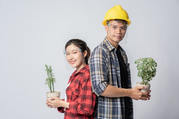 Men and women standing and holding plant pots in the house